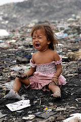 Child sitting in the middle of a dump.